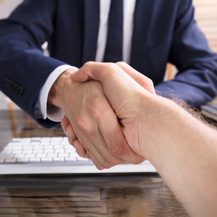 Two men in a meeting shaking hands as a result of an agreement.